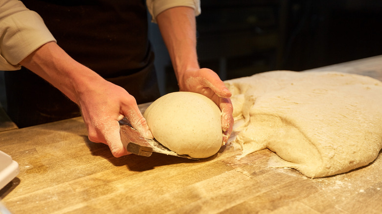 Bench scraper picking up dough ball