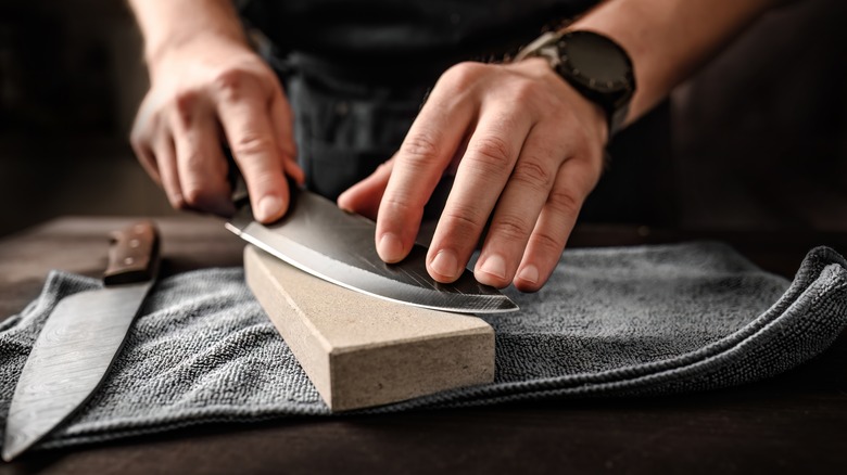 Man sharpening knife on whetstone