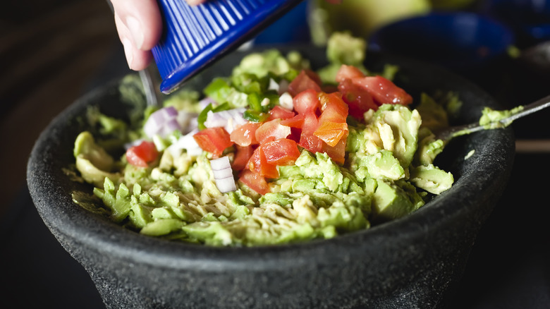 Tomatoes and onions into guacamole