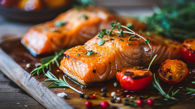 Salmon fillets beautifully plated on wooden board with herbs.