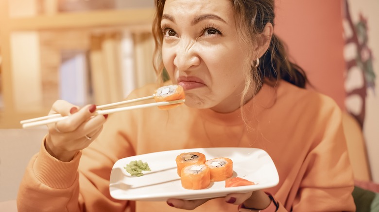 woman sniffing bad sushi roll